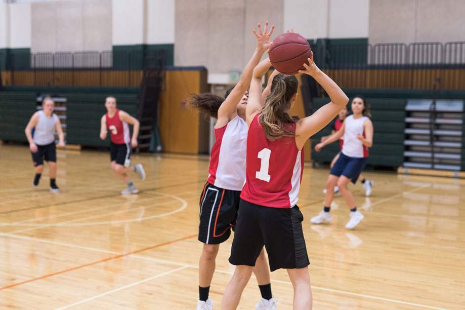 youth basketball team player in red uniform trying to pass the ball while player in white uniform defends