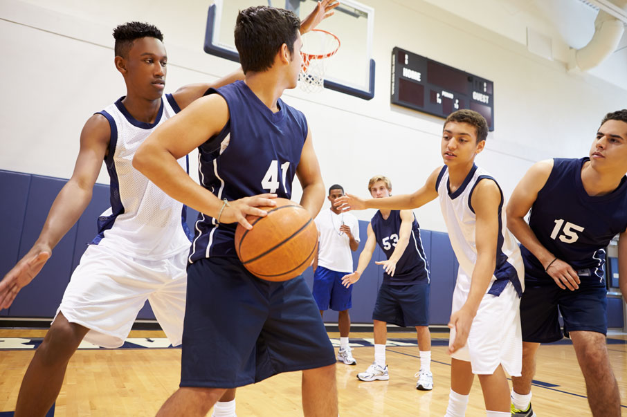 youth basketball team players player in blue uniforms holding ball while players in white uniforms defend
